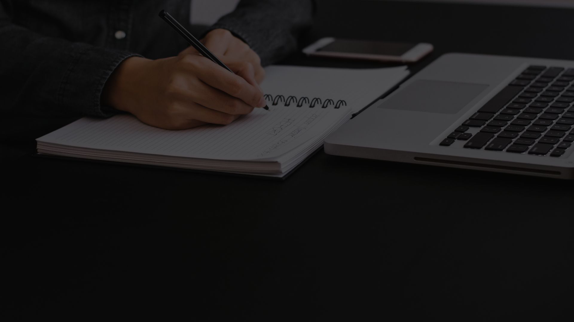 person writing on pen pad with laptop out